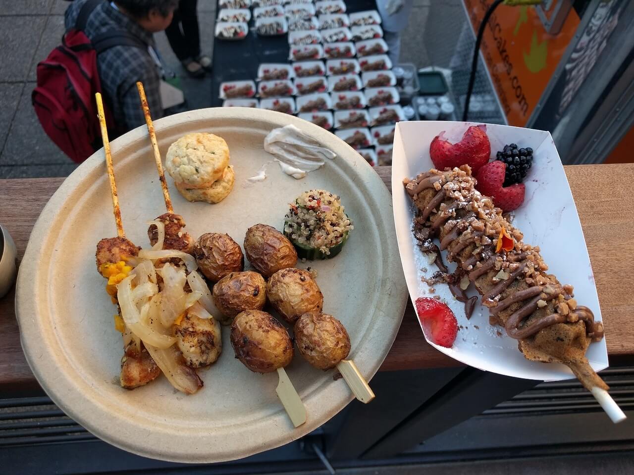 View of my dinner plate with chicken skewers, salt potato skewers, and other snacks, alongside a dessert treat on a stick.