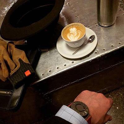 Looking down at my arm in a suit resting next to a cappuccino, watch visible below sleeve.